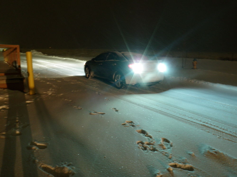 Автомобиль едет задним ходом ночью зимой по снегу